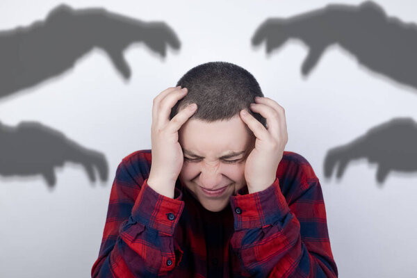 The man is experiencing a panic attack. The concept of phobia, fears, paranoia and persecution mania. Shadow silhouettes surrounded the man. Nervous breakdown and nervous disorders