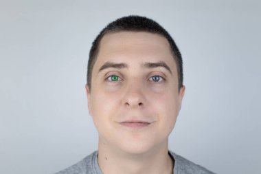 Farklı renkte gözleri olan bir adam çerçeveye bakar. Sağ gözü mavi, sol gözü yeşil. Heterokromi. Gen mutasyonu. Çok renkli gözler..