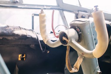 Eski bir uçağın kokpitine yakın çekim. Direksiyon, gösterge paneli, koltuk ve tırmanma kolları görünür durumda. Devre dışı bırakılmış uçak. Her şey zaman zaman kırılır ve hasar görür..