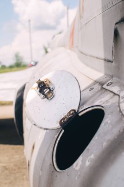 Açık yakıt sistemi olan eski bir askeri savaş uçağının gövdesinin bir kısmına yakın çekim. Uçağın açık tankı, metal kapağı açıkça görülüyor.