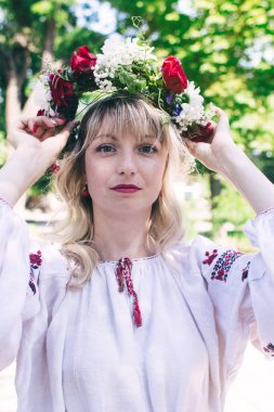 Geleneksel halk kostümüyle poz veren genç bir kadın. Çelenkli ve nakışlı gömlekli Kazak kız. Eski gelenek ve geleneklerin yeniden inşası. Klasik tarihi kıyafet.