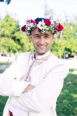 Geleneksel halk kostümü giymiş genç bir adam. Çelenk ve nakışlı gömlekli bir Kazak erkeği. Eski gelenek ve geleneklerin yeniden inşası. Klasik tarihi kıyafet.