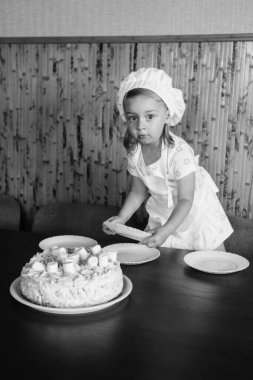 Çocuklar mutfakta aileleriyle yemek pişiriyor. Bütün aile için ev yapımı kek, pasta ya da kurabiye yapıyorum. Mutlu çocukluk kavramı. Mutfak önlükleri ve şef şapkaları takan küçük ikiz kardeşler.