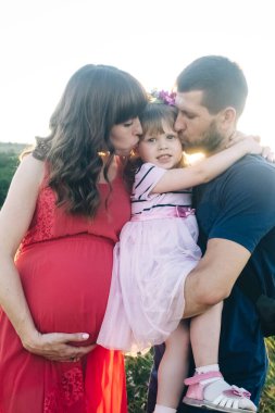 Baba ve kızı hamile bir kadına bakıyor. Aile ikinci bir çocuk bekliyor. Küçük kız kardeşi erkek kardeşini bekliyor. Sevgi dolu akrabalar hamile karnını öper ve okşarlar.