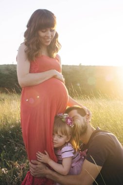 Baba ve kızı hamile bir kadına bakıyor. Aile ikinci bir çocuk bekliyor. Küçük kız kardeşi erkek kardeşini bekliyor. Sevgi dolu akrabalar hamile karnını öper ve okşarlar.