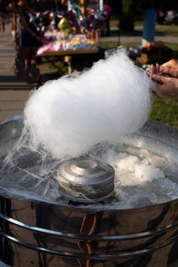 Pamuk helva yapan bir adamın yakın çekimi. Tahta sopa, tatlı örümcek ağının iplerini saracak. Tatlı bulut ve eritilmiş ikram makinesi. Sokak yemekleri ve karnaval lezzeti kavramı..