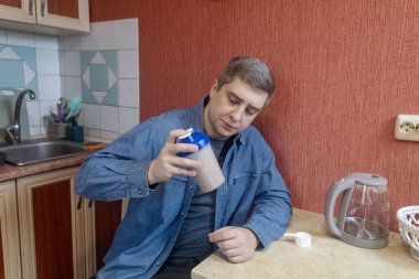 Adam mutfakta protein içeceği hazırlıyor. Tozu fitness, iyileşme ve kas sağlığı için karıştırıcıya dönüştürüyor..