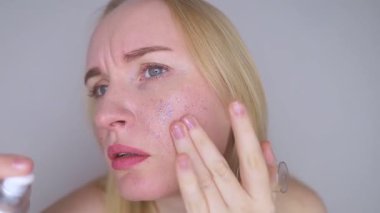 Kozmetik alanında mikroplastikler. Bir kadın cildine bakım kremi sürmüş, şimdi plastik parçacıklar ve mikroboncuklarla kaplanmış. Kozmetik zehirlenmesi konsepti