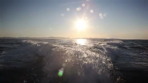 Zonsondergang met golven achter boot — Stockvideo