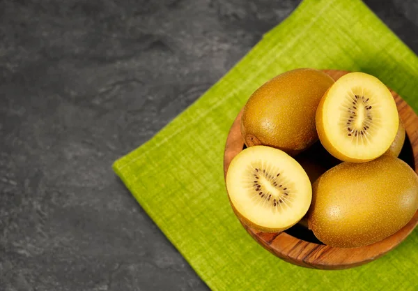 Kiwi Zlaté Žluté Ovoce Dřevěné Míse Jedním Plátky Kiwi Šedém — Stock fotografie