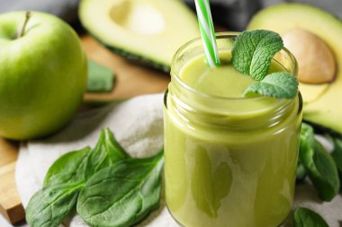 Avokado ıspanağı ve yeşil elma püresi sağlıklı ve ferahlatıcı tropikal bir içecek. Naneli cam kavanoz ve dilimlenmiş avokado meyvesi, elma ve ıspanak yaprakları..