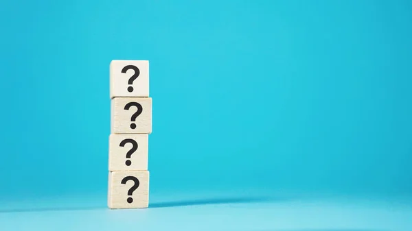 Question mark symbol and sign on 4 wooden blocks cubes on blue background, customer questions, faqs and business assistance concept.