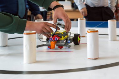 Öğrencinin elleri STEM yarışması başlamadan önce DIY robotunun sensörlerini ayarlıyor.