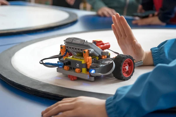 Blok bazlı bir programlama ortamında dizüstü bilgisayar üzerinde çalışan bir öğrencinin yakın çekimi. Yakınlarda yapılı bir robot duruyor. Modern eğitim ve bilişim becerileri kavramı.