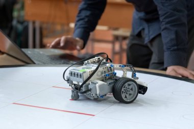Özel bir LEGO zihin fırtınası programlayan robotik öğrencisi, bir sınıf ortamında bir yarışma pistinde robot programlıyor