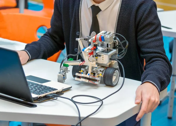 Sınıfta DIY eğitim robotu programlayan bir öğrenci. Üniformalı bir öğrenci, sofistike programlanabilir bir robotu kodlamak ve test etmek için bir masada oturuyor. STEM eğitimi kavramı