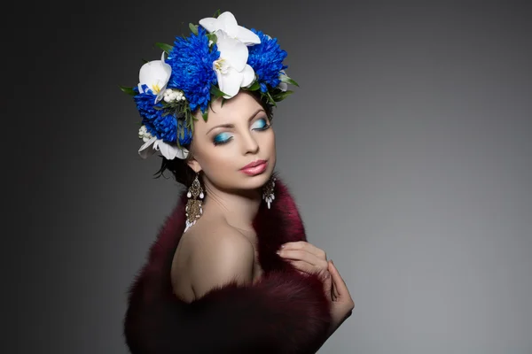 Woman with a wreath of flowers on her head in a fur coat. Young Stock Fotografie