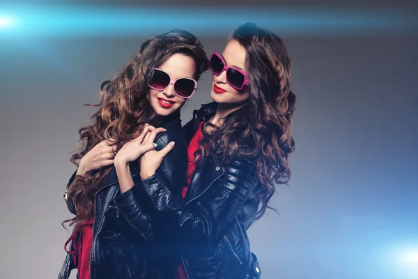 Systrarna tvillingar i hipster solglasögon skrattar två mode modeller Royaltyfria Stockfoton