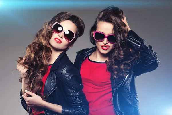 Systrarna tvillingar i hipster solglasögon skrattar två mode modeller Stockbild