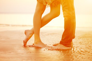 sevgi dolu bir genç çifte sarılma ve gün batımında sahilde öpüşme