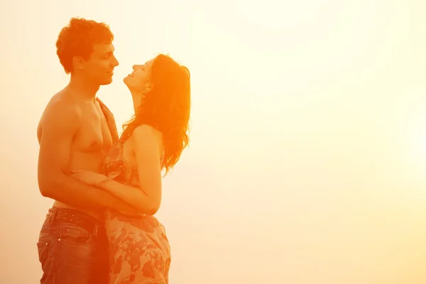 Una giovane coppia amorevole che abbraccia e bacia sulla spiaggia ai soli — Foto Stock