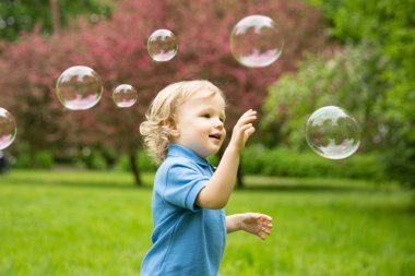 Cute curly baby with soap bubbles. children playing,  running A 