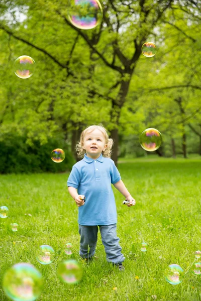 Niedlichen lockigen Baby mit Seifenblasen. Kinder spielen, laufen eine — Stockfoto