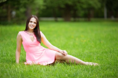 Young spring fashion woman sitting on the grass. Trendy girl in 