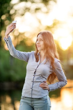Romantic young girl holding a smartphone digital camera with her