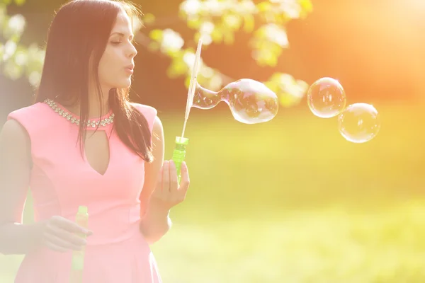 Young spring fashion woman blow bubbles. Trendy girl in the flow — Stock fotografie