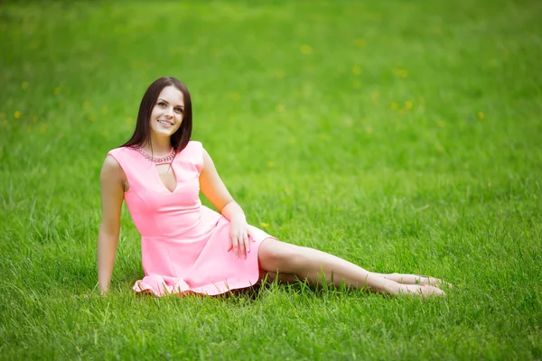 Young spring fashion woman sitting on the grass. Trendy girl in — Stockfoto