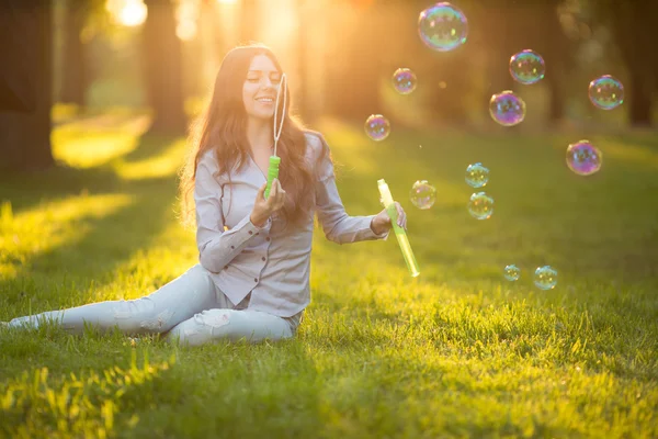 Young spring fashion casual woman blow bubbles in the sunset in — 图库照片