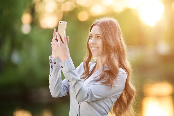 Romantic young girl holding a smartphone digital camera with her — Stock fotografie