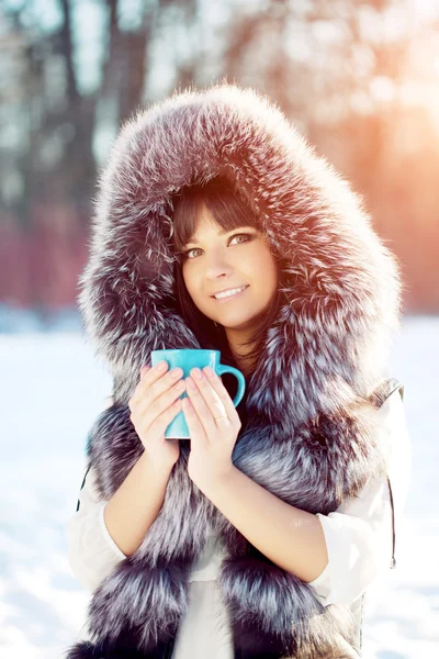 Giovane donna con una tazza di bevanda calda Donna invernale su sfondo o — Foto Stock