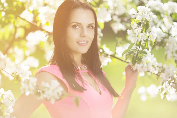 Young spring fashion woman. Trendy girl in the flowering trees in the spring summer garden. Springtime or summertime. Lady in spring landscape background. Allergic to pollen of flowers. Spring allergy Royalty Free Stock Images