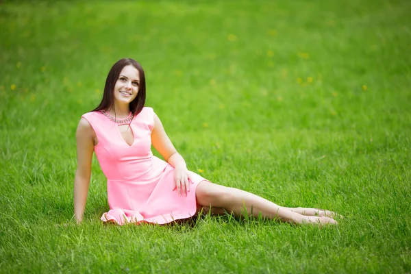 Young spring fashion woman sitting on the grass. Trendy girl in Stockfoto