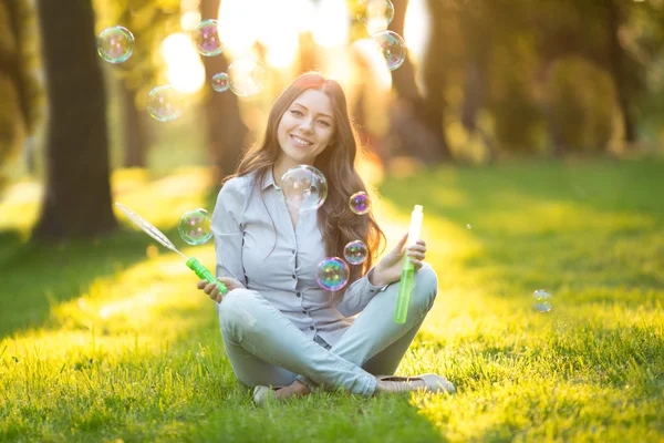 Young spring fashion casual woman blow bubbles in the sunset in Royalty Free Stock Fotografie