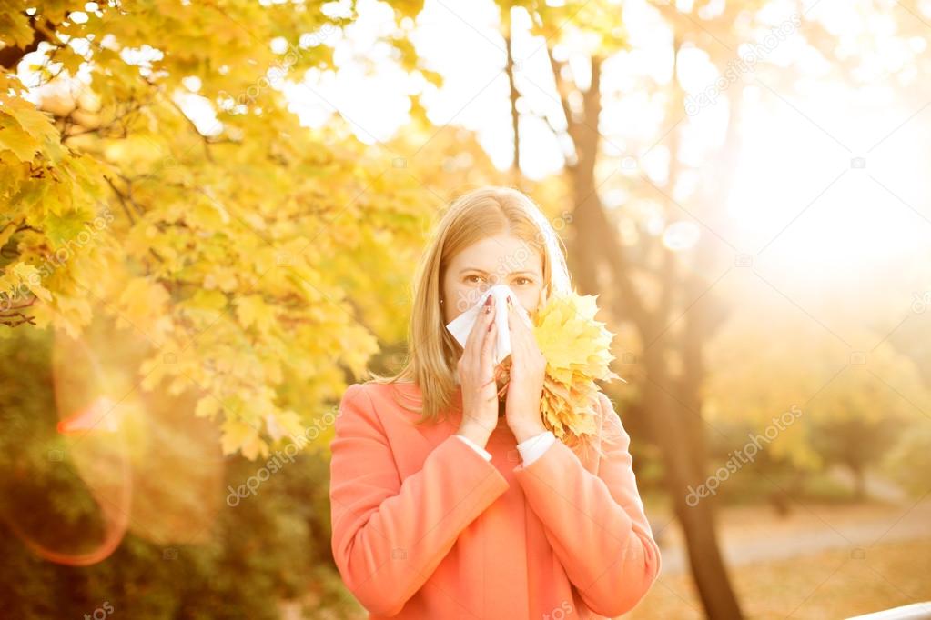 Girl with cold rhinitis on autumn background. Fall flu season. I