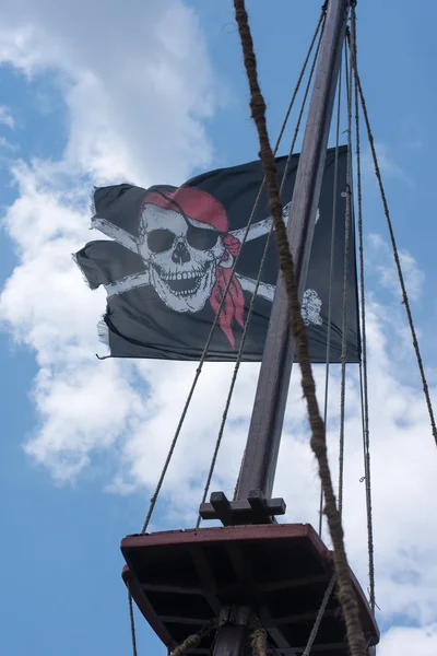 Una bandera pirata de cráneo y huesos cruzados ondeando en el viento — Foto de Stock