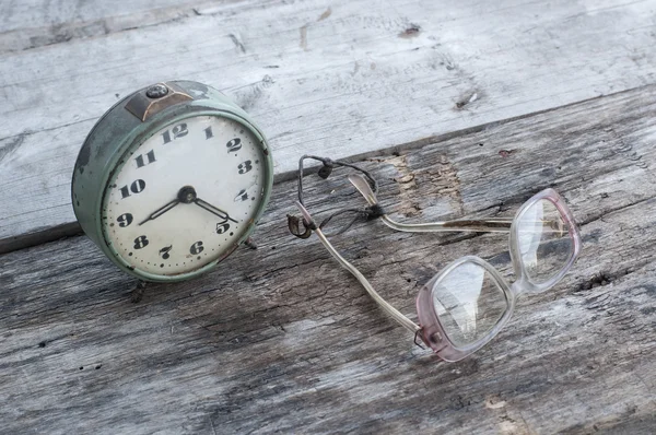 Relógio e copos em uma mesa de madeira — Fotografia de Stock