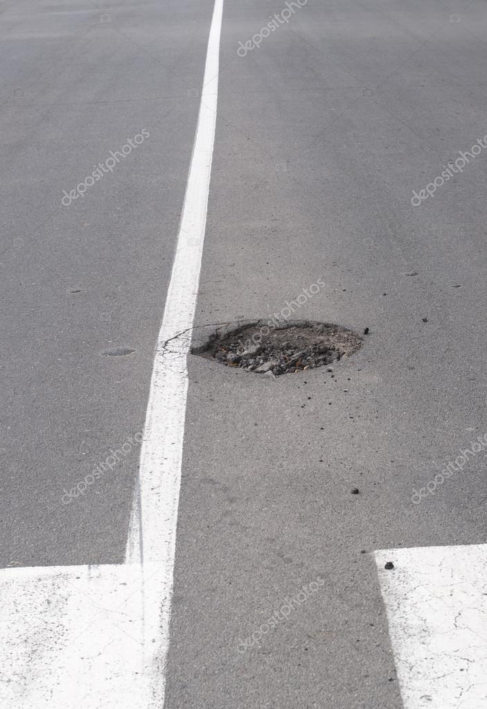 Potholes on a road with white dividing lines