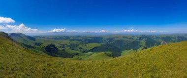 Büyük doğa sıradağları. Kafkas dağının yeşil tarlalı, mavi gökyüzü arka planlı panorama perspektifi. Elbrus manzara manzarası - Rusya ve Avrupa 'nın en yüksek zirvesi