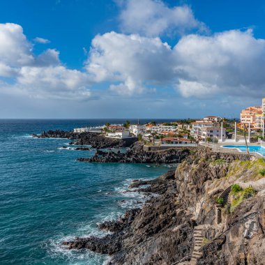 Tropik Tenerife adası. Tenerife adasında havuzlu binaları olan sahil şeridinin panoraması. Arkaplan mavisi gökyüzü rengi