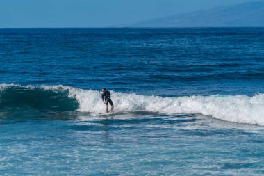 Dalgadaki sörfçü. Sörfçü bir dalganın tepesinde yakalar ve döner. Tenerife adasında dalgalar.