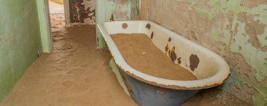 Alman Kolmanskop 'unda kum dolu bir küvet Namibya' daki terk edilmiş binaları olan Kolmannskuppe Hayalet Kasabası.