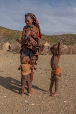 Himba köyünde Himba kabilesinden iki erkek çocuğu olan kadın, dikey.