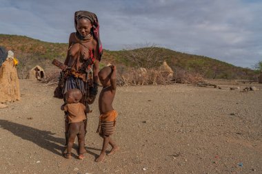 Himba köyünde Himba kabilesinden iki oğlu olan bir kadın.