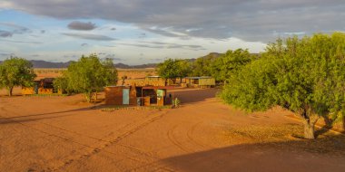 BETTA, NAMIBIA - HAZİRAN 05.2021: Namib Naukluft Milli Parkı, Namibya 'da gün batımında Kalahari Çölü' ndeki binalarla Betta Kampı