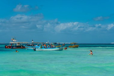 ISLA MUJERES, MEXICO - 12 Mart. 2021: Playa Norte - kristal berrak turkuaz suyu ve teknesi olan insanlar, Isla Mujeres