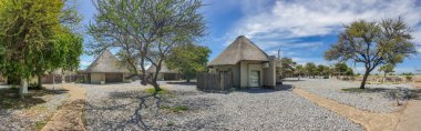OKAUKUEJO, NAMIBIA - 14 Ocak 2020: Okaukuejo oteli sazdan çatı evleri ve havuzu Etosha Milli Parkı, Panorama